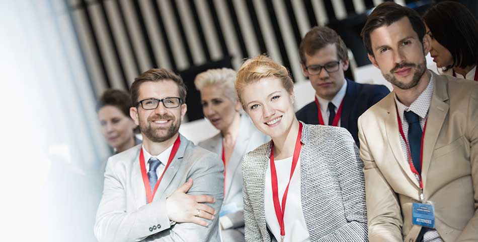 Conference attendees wearing red custom lanyards with ID badges at a business event for secure credential display and professional branding