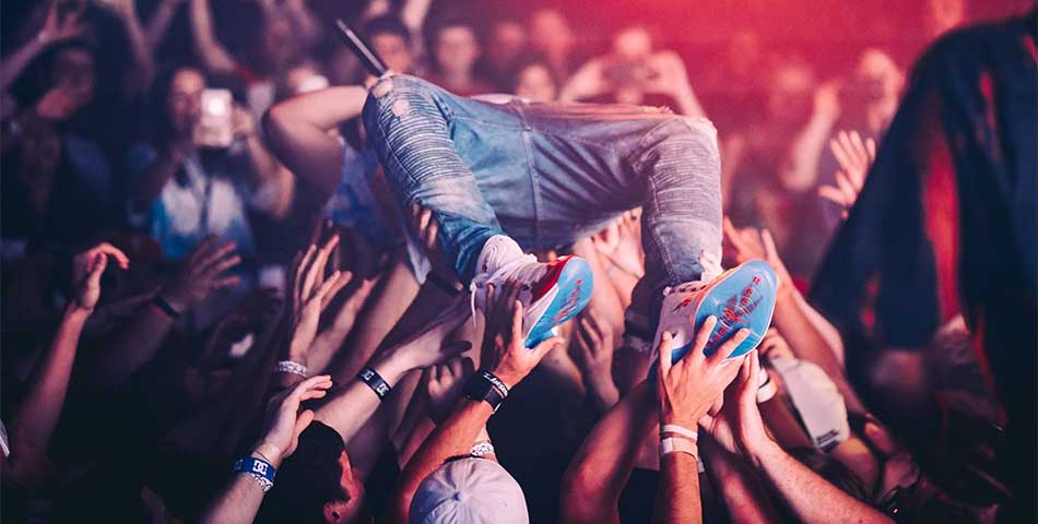 Crowd surfing at a live concert with attendees wearing event admission wristbands for entry and access control