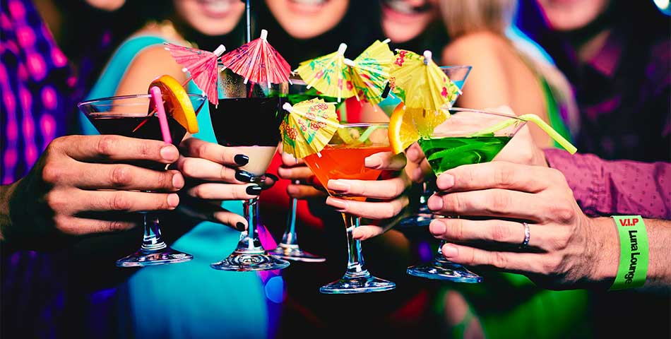 Group of friends holding cocktails while wearing VIP and age-verified bar wristbands at a nightclub entrance